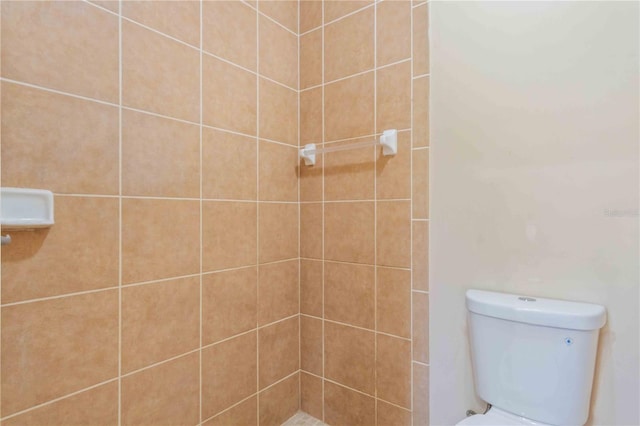 bathroom with a tile shower and toilet