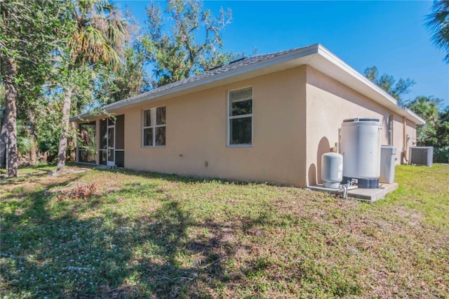 rear view of property featuring a lawn and central air condition unit