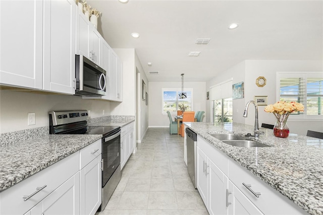 kitchen with light stone countertops, appliances with stainless steel finishes, sink, pendant lighting, and white cabinets