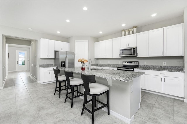 kitchen featuring a center island with sink, sink, a kitchen bar, white cabinetry, and stainless steel appliances