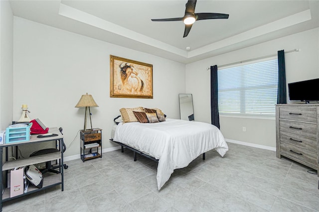 bedroom with a tray ceiling, ceiling fan, and light tile patterned flooring