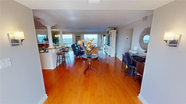 interior space with hardwood / wood-style floors, ornamental molding, and decorative columns