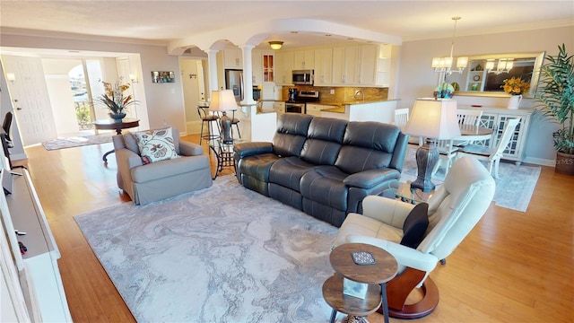 living room featuring light hardwood / wood-style floors, a notable chandelier, and ornamental molding