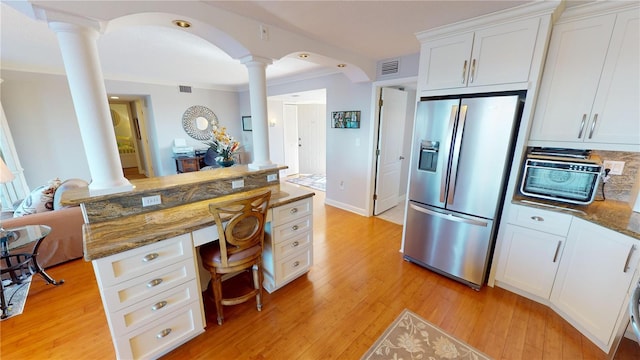 kitchen featuring a kitchen bar, dark stone counters, white cabinets, stainless steel fridge with ice dispenser, and light hardwood / wood-style floors