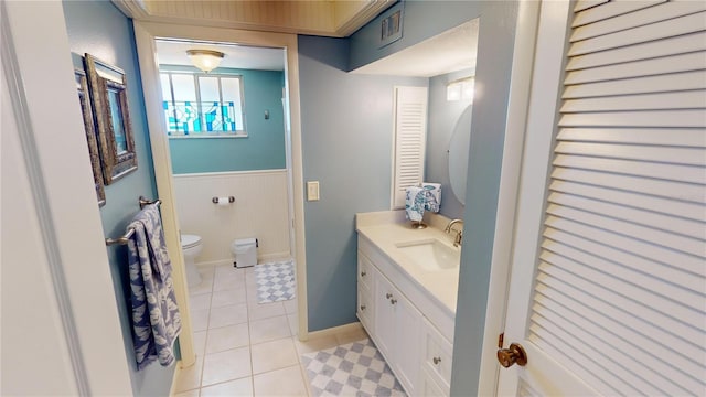 bathroom featuring toilet, vanity, tile patterned floors, and wooden walls