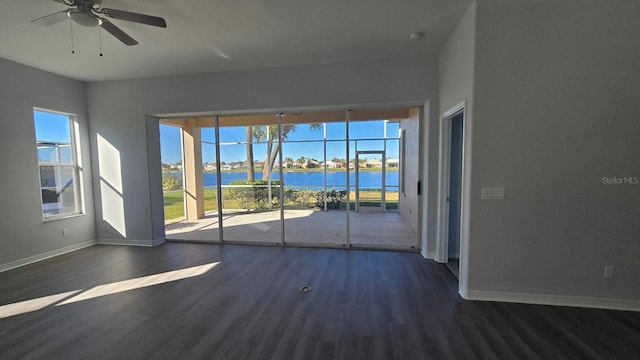 spare room with a wealth of natural light, dark hardwood / wood-style flooring, and a water view