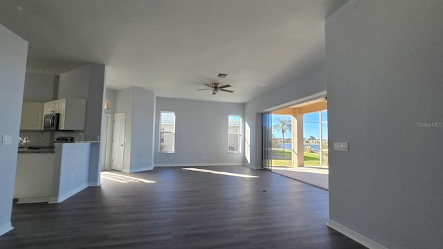 unfurnished living room featuring dark hardwood / wood-style flooring and ceiling fan