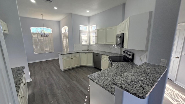 kitchen featuring dark wood-type flooring, sink, decorative light fixtures, kitchen peninsula, and stainless steel appliances