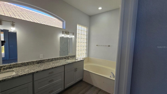 bathroom with a washtub, vanity, and hardwood / wood-style flooring