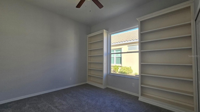 spare room featuring dark carpet and ceiling fan