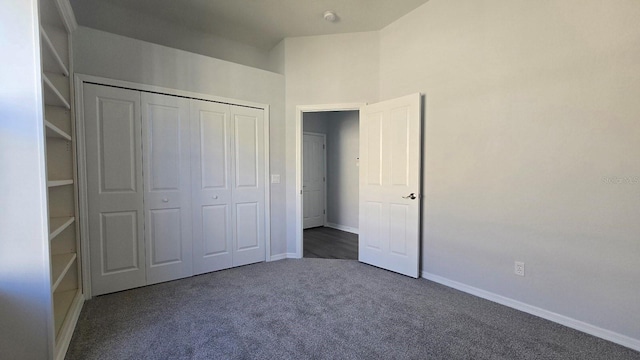 unfurnished bedroom with dark carpet and a closet