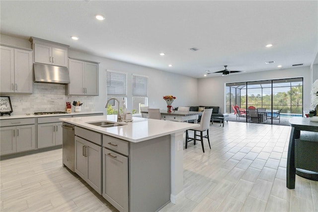 kitchen featuring ceiling fan, gray cabinets, sink, and an island with sink