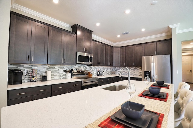 kitchen featuring dark brown cabinetry, sink, stainless steel appliances, backsplash, and a kitchen bar