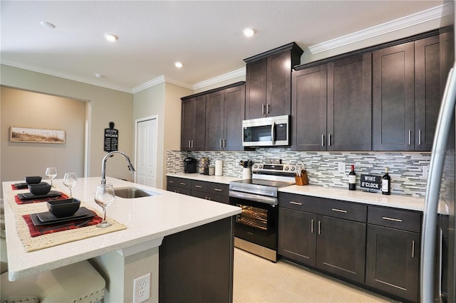 kitchen with a center island with sink, sink, ornamental molding, tasteful backsplash, and stainless steel appliances