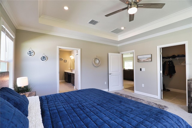 bedroom featuring ceiling fan, a spacious closet, ensuite bathroom, a tray ceiling, and a closet