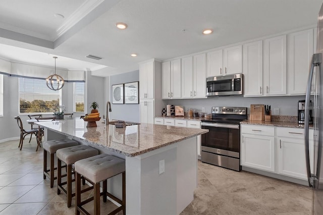 kitchen with white cabinets, appliances with stainless steel finishes, and an island with sink