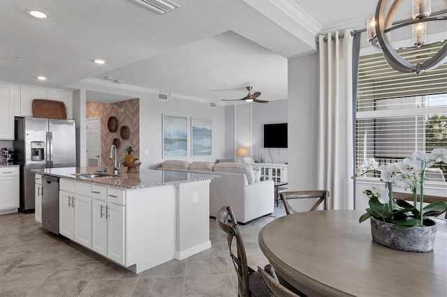 kitchen featuring sink, white cabinets, an island with sink, and ornamental molding