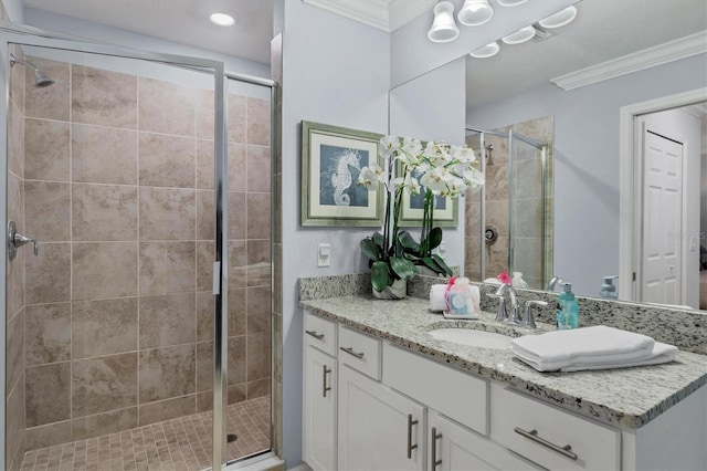 bathroom featuring vanity, ornamental molding, and a shower with door