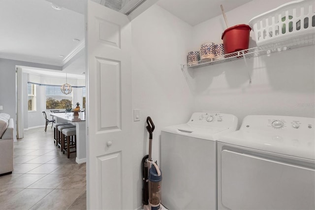 laundry room with washer and dryer, ornamental molding, and light tile patterned flooring