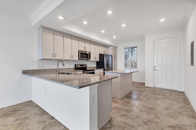 kitchen with kitchen peninsula, appliances with stainless steel finishes, a kitchen island, and sink