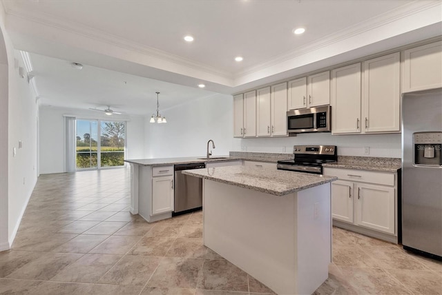 kitchen with kitchen peninsula, ceiling fan with notable chandelier, stainless steel appliances, sink, and hanging light fixtures