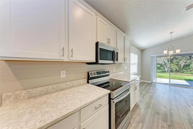 kitchen featuring white cabinetry, stainless steel appliances, a chandelier, lofted ceiling, and light hardwood / wood-style floors