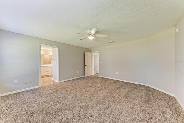 unfurnished bedroom with a textured ceiling, ceiling fan, light carpet, and ensuite bath