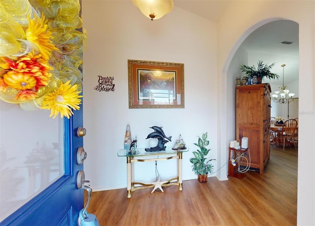 foyer entrance featuring hardwood / wood-style floors, an inviting chandelier, and lofted ceiling