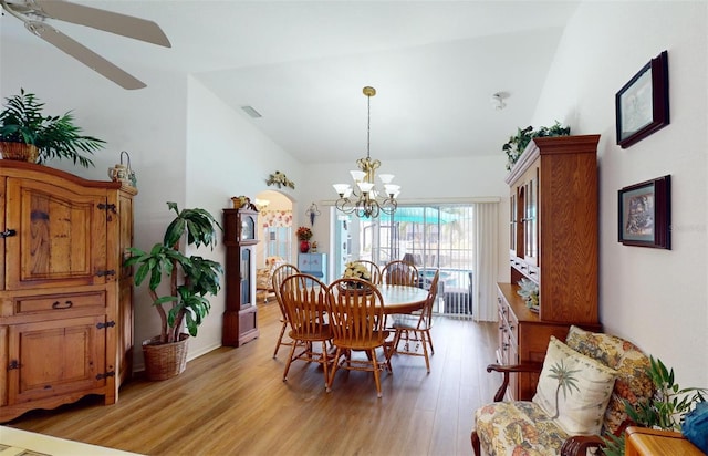 dining space featuring ceiling fan with notable chandelier, light hardwood / wood-style floors, and lofted ceiling