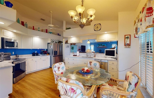 kitchen with light wood-type flooring, ceiling fan with notable chandelier, stainless steel appliances, decorative light fixtures, and white cabinetry