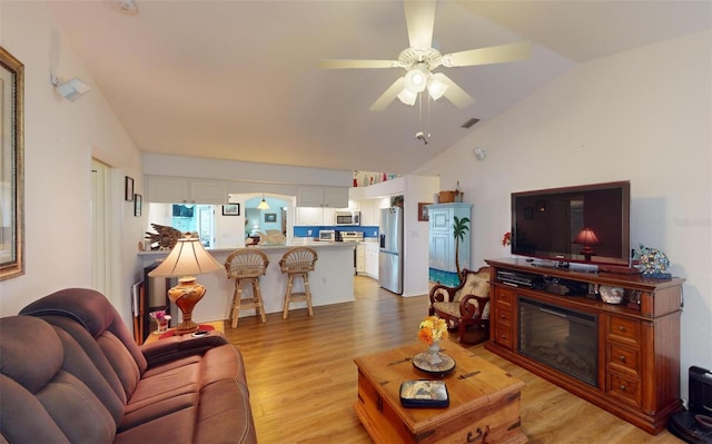 living room with ceiling fan, lofted ceiling, and light hardwood / wood-style flooring