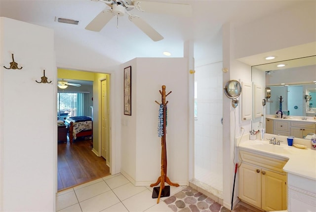 bathroom with hardwood / wood-style flooring, vanity, and a tile shower