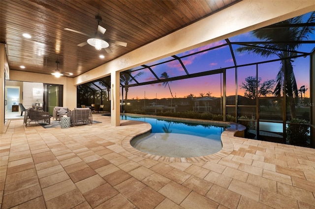 pool at dusk with a patio area, ceiling fan, glass enclosure, and an outdoor hangout area