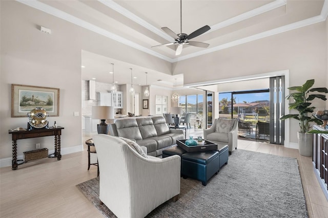 living room featuring ceiling fan, crown molding, a high ceiling, and a tray ceiling