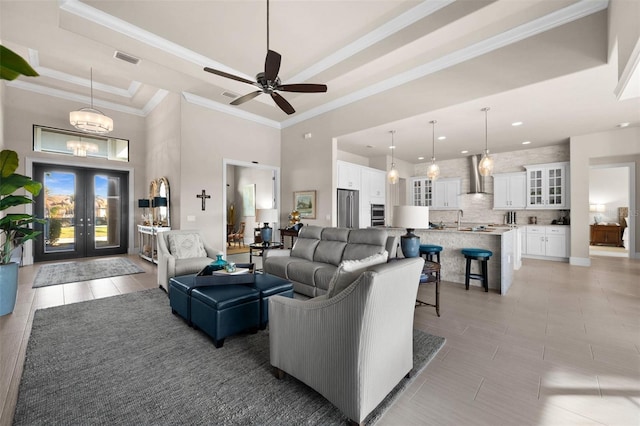 living room with french doors, ceiling fan with notable chandelier, crown molding, light tile patterned floors, and a high ceiling