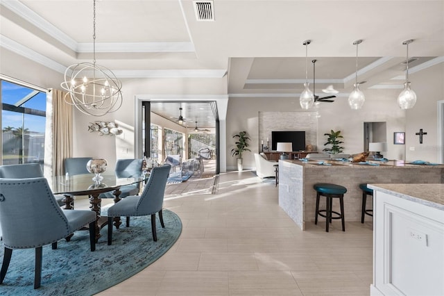 dining space with ceiling fan with notable chandelier, a tray ceiling, ornamental molding, and light tile patterned flooring