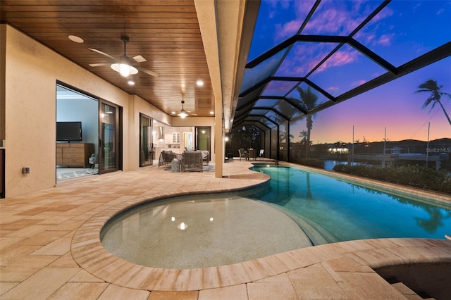 pool at dusk featuring ceiling fan, a lanai, an outdoor living space, and a patio