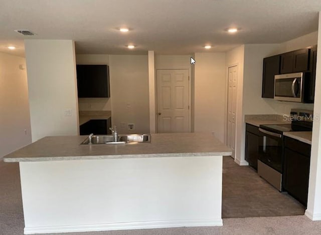 kitchen with light carpet, appliances with stainless steel finishes, a center island with sink, and sink