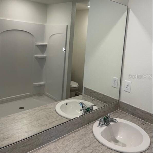 bathroom featuring walk in shower, vanity, and toilet