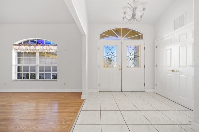 entrance foyer with french doors, light wood-type flooring, and an inviting chandelier