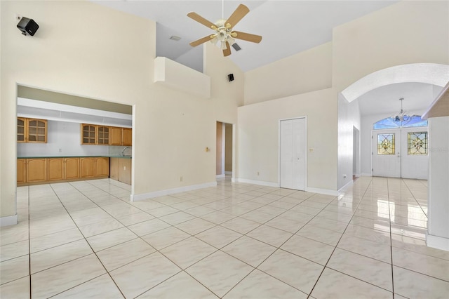 interior space with french doors, light tile patterned floors, high vaulted ceiling, and ceiling fan with notable chandelier