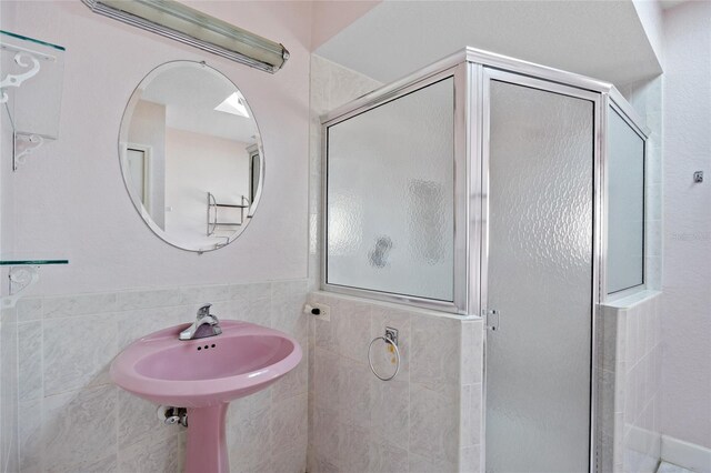 bathroom with tile walls and a shower with shower door