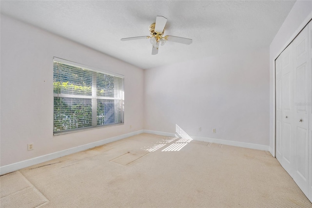 carpeted empty room featuring a textured ceiling and ceiling fan