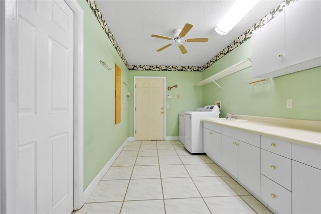 clothes washing area with ceiling fan, cabinets, washing machine and dryer, a textured ceiling, and light tile patterned floors