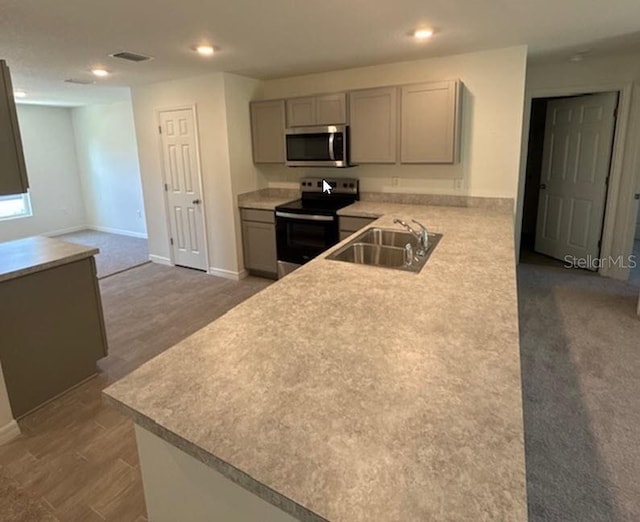 kitchen with gray cabinetry, dark carpet, sink, kitchen peninsula, and stainless steel appliances