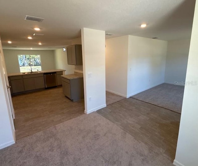 kitchen with dishwasher, sink, and light carpet