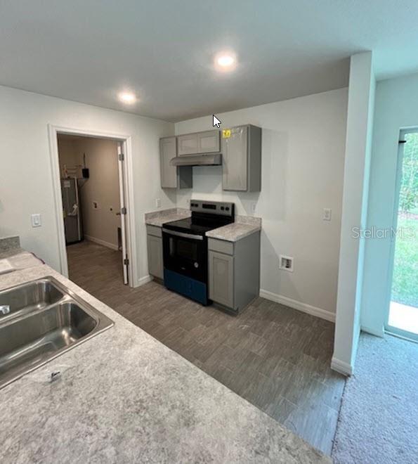 kitchen with gray cabinetry, dark hardwood / wood-style flooring, a healthy amount of sunlight, and black range with electric cooktop