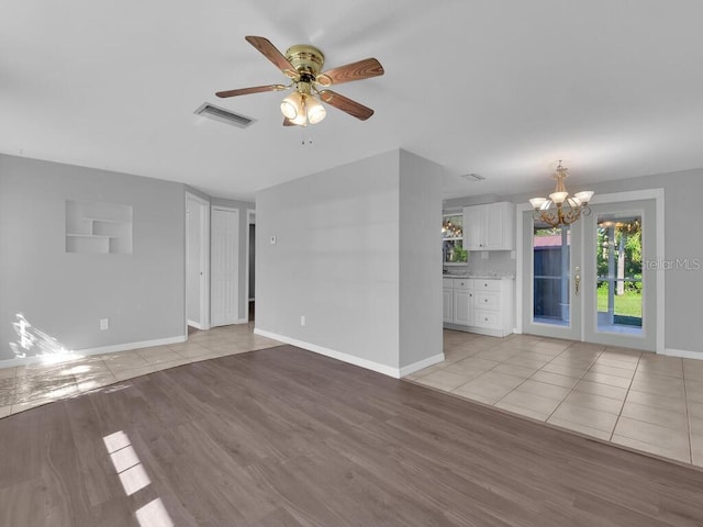 unfurnished living room with light hardwood / wood-style flooring and ceiling fan with notable chandelier