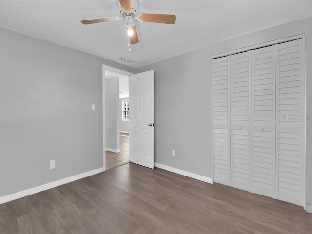 unfurnished bedroom with hardwood / wood-style floors, ceiling fan, and a closet