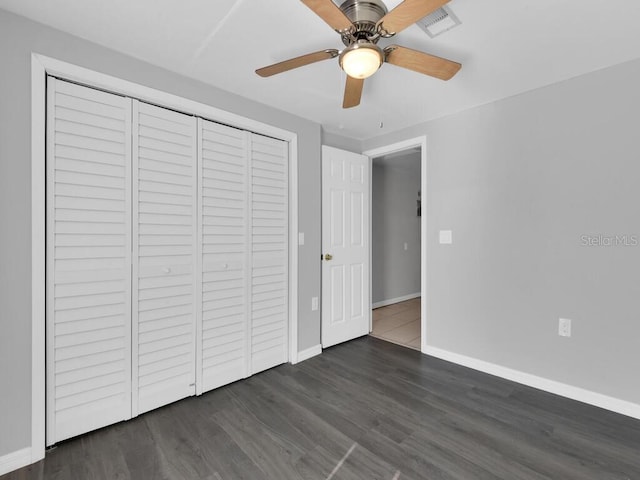 unfurnished bedroom featuring ceiling fan, a closet, and dark wood-type flooring